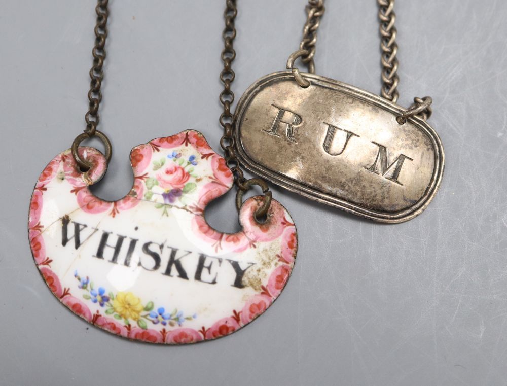 An early Victorian silver Rum wine label, Rawlings & Summers, London, 1839, 4cm and an enamelled whisky label(a.f.).